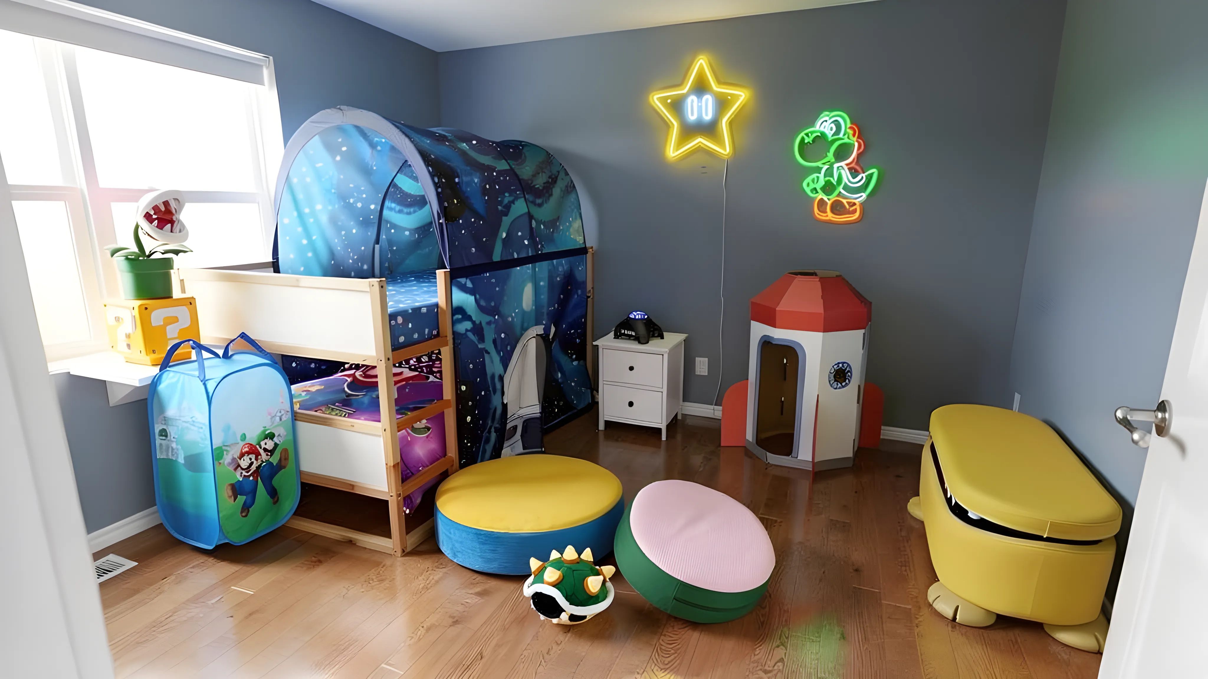 A bright cobalt-blue Super Mario Galaxy themed kids' bedroom with bunk beds, Mario-printed bedding, a starry tent canopy over the top bunk, a rocket-ship playhouse on a striped rug, a Question Block lamp on a side table, neon Star and Piranha Plant wall signs, two yellow round pouffes, and a small projector. Daylight streams through the window.